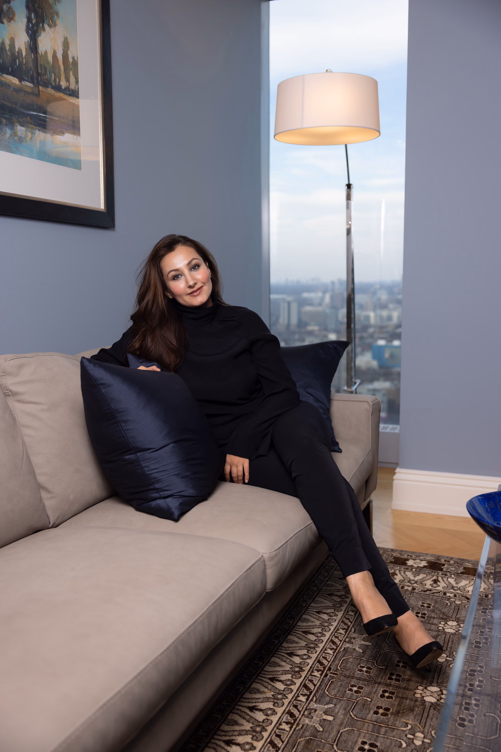 Dewa Patang seated on a sofa with the city skyline behind