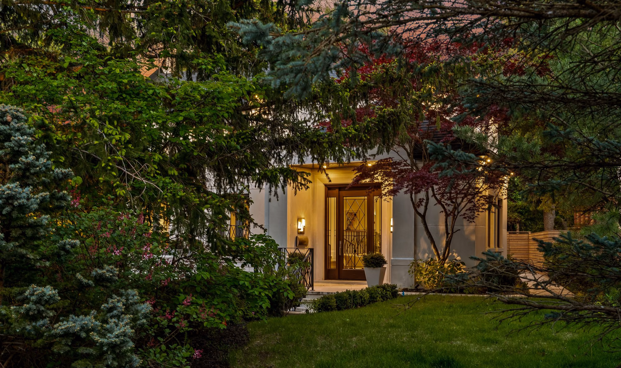 Front entry seen through lush garden greenery at dusk