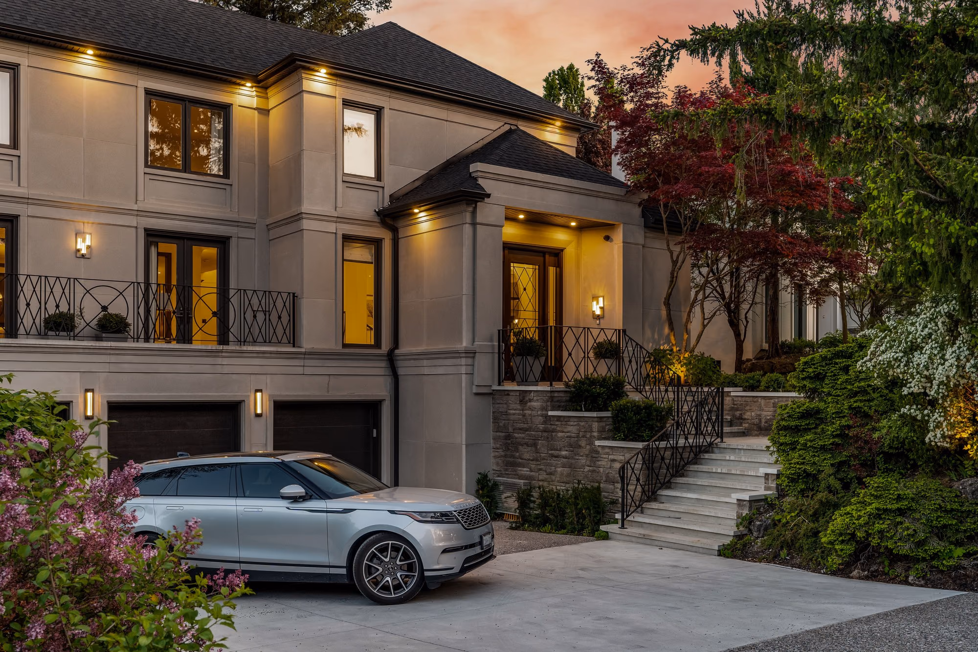 Stone home exterior at dusk with a car parked in the driveway