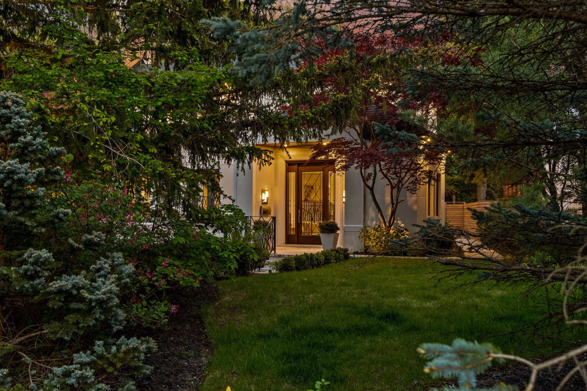 Front entry seen through lush garden greenery at dusk