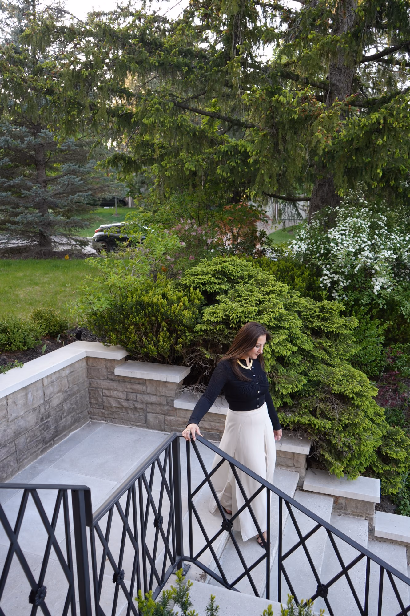 Woman on garden terrace steps with an iron railing