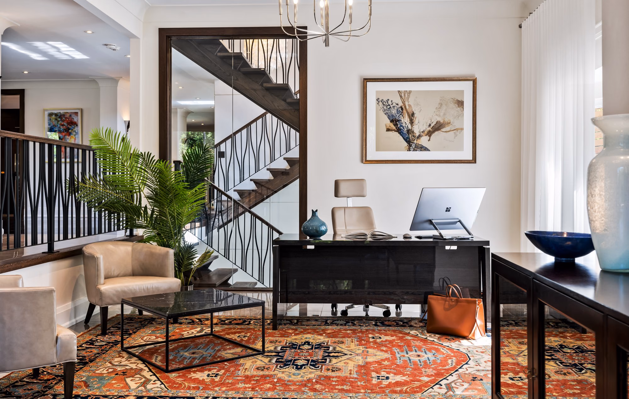 Home office with staircase, persian rug and dark wood desk