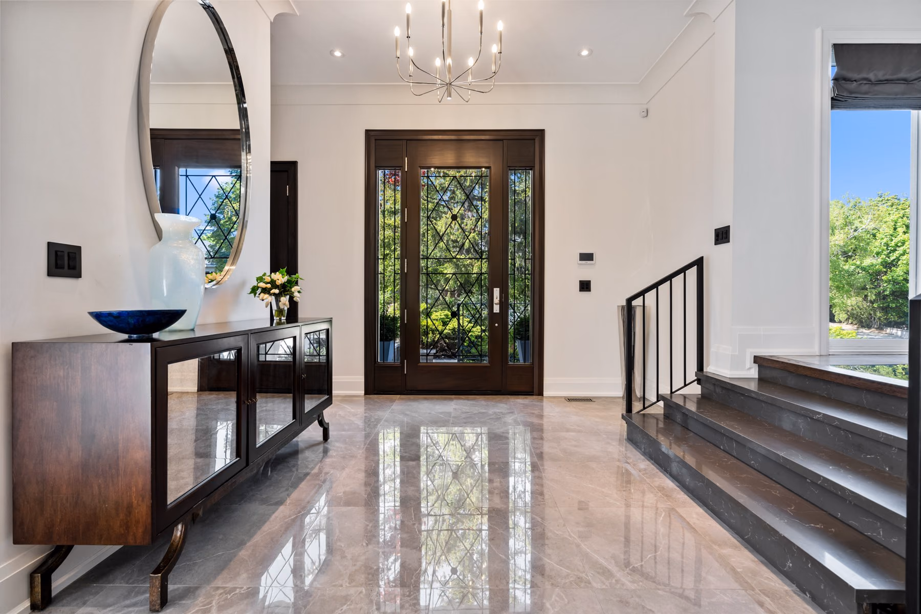 Foyer with polished marble floor, round mirror and console