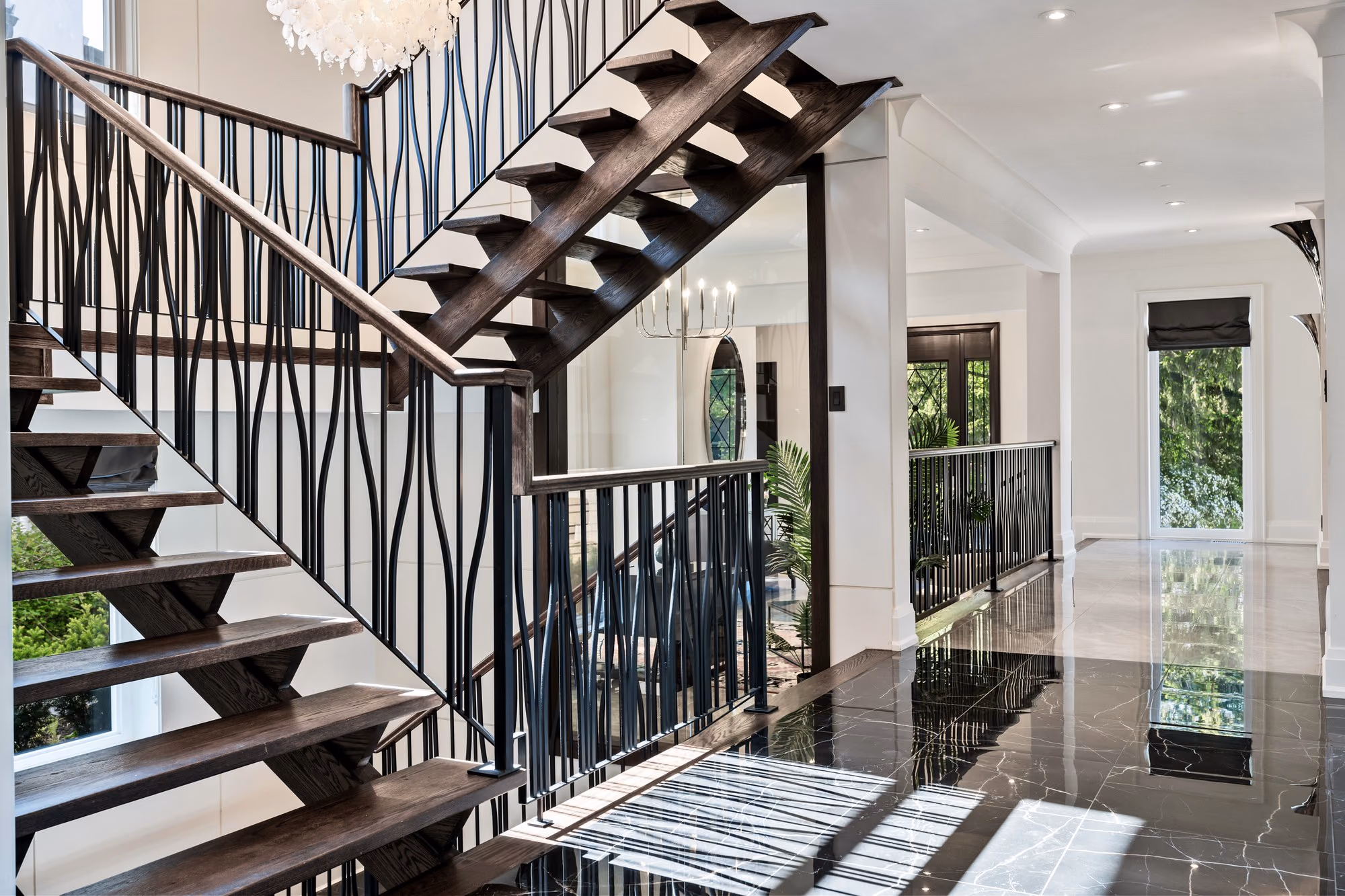 Floating wood staircase with iron balusters beside the front entry