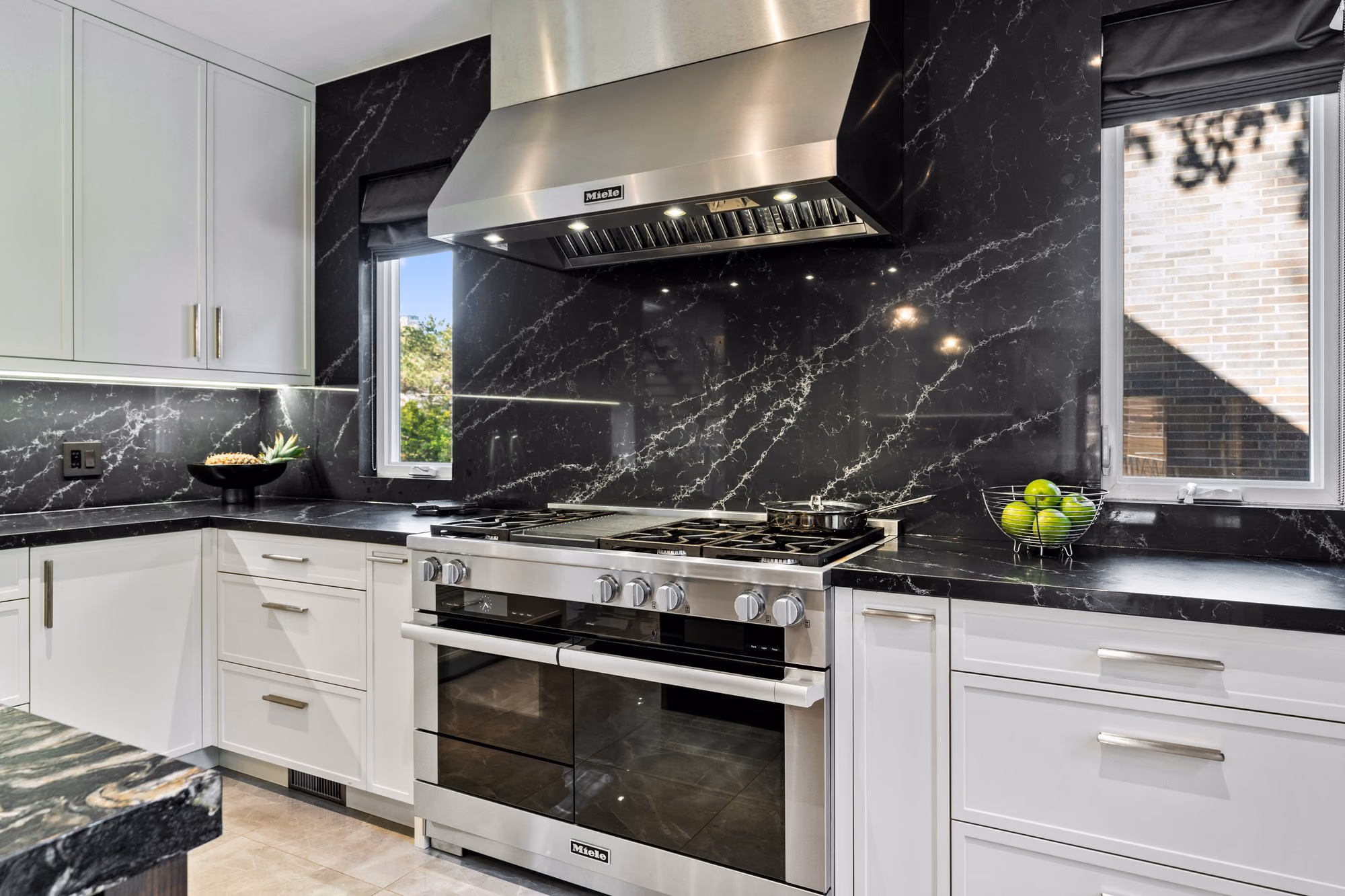 White kitchen with professional range and dark marble backsplash