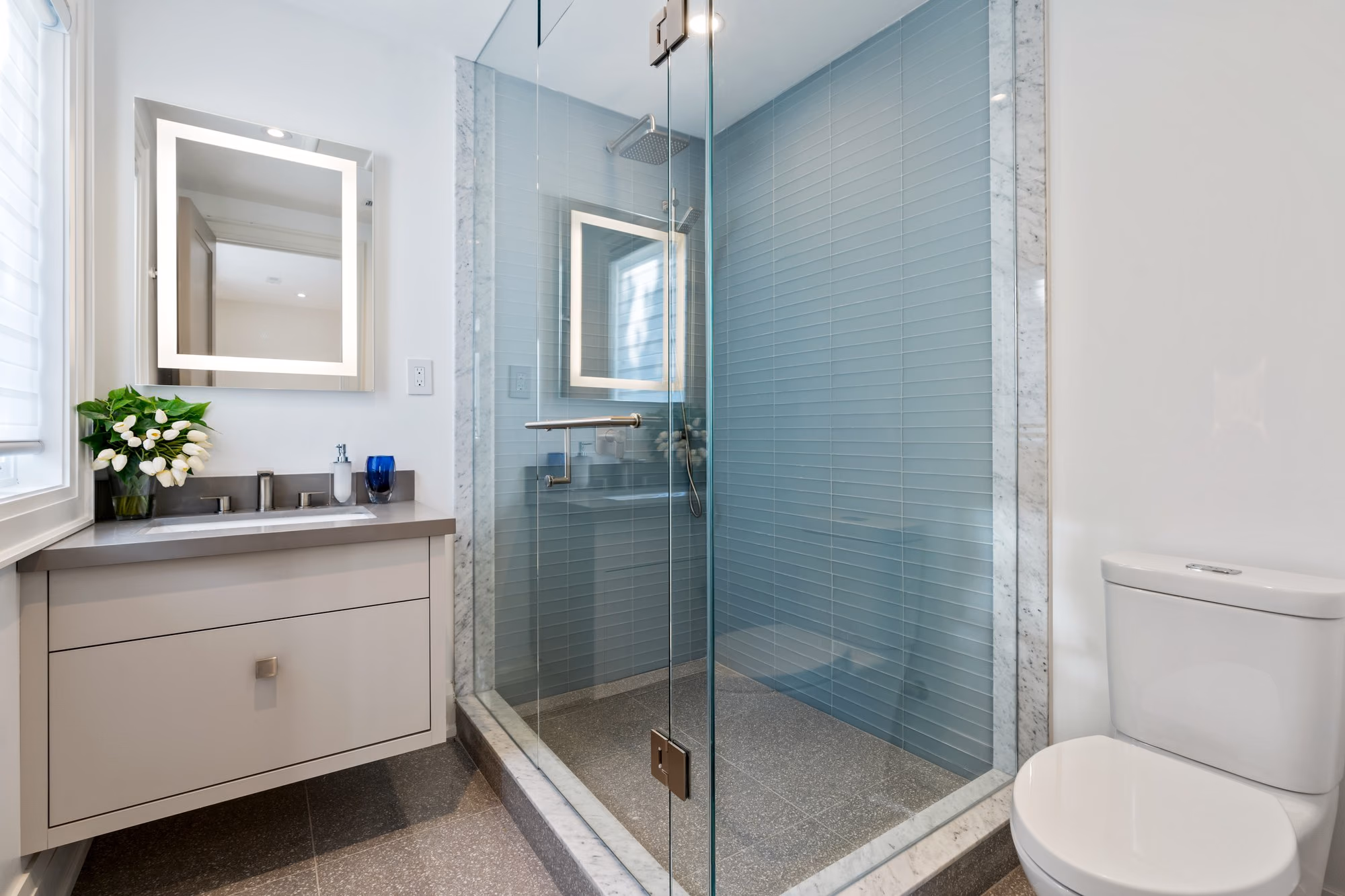 Blue-tiled shower with glass enclosure and vanity