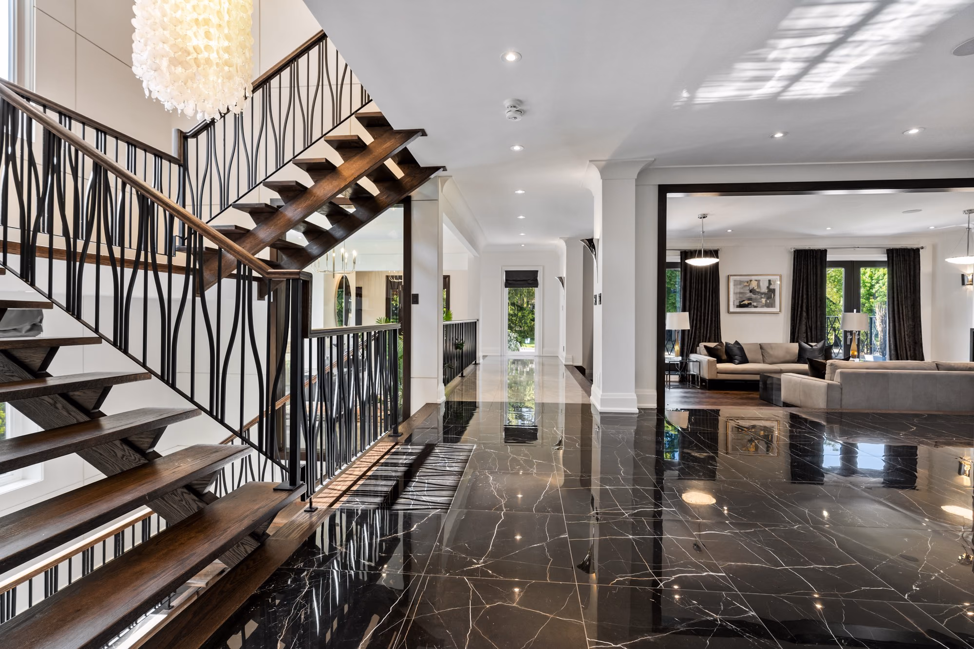 Sculptural staircase over black marble floor beside the living room