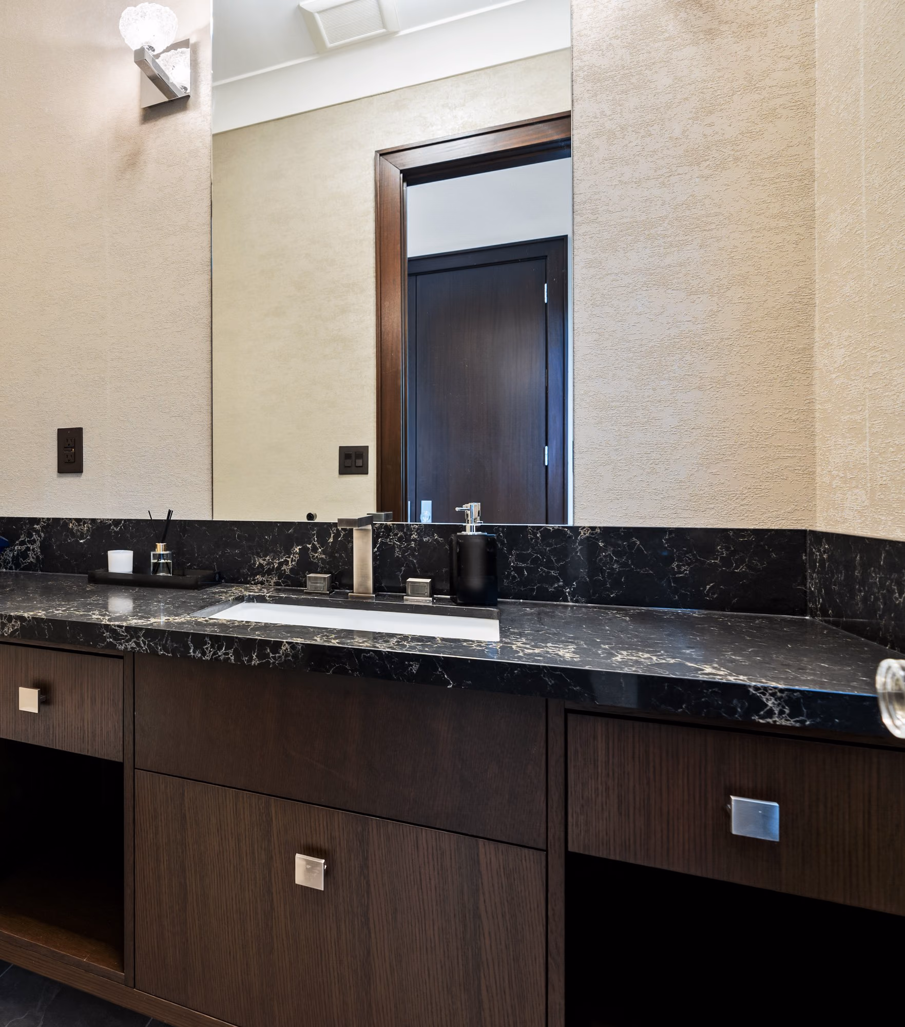 Powder room with dark stone counter and wood cabinetry