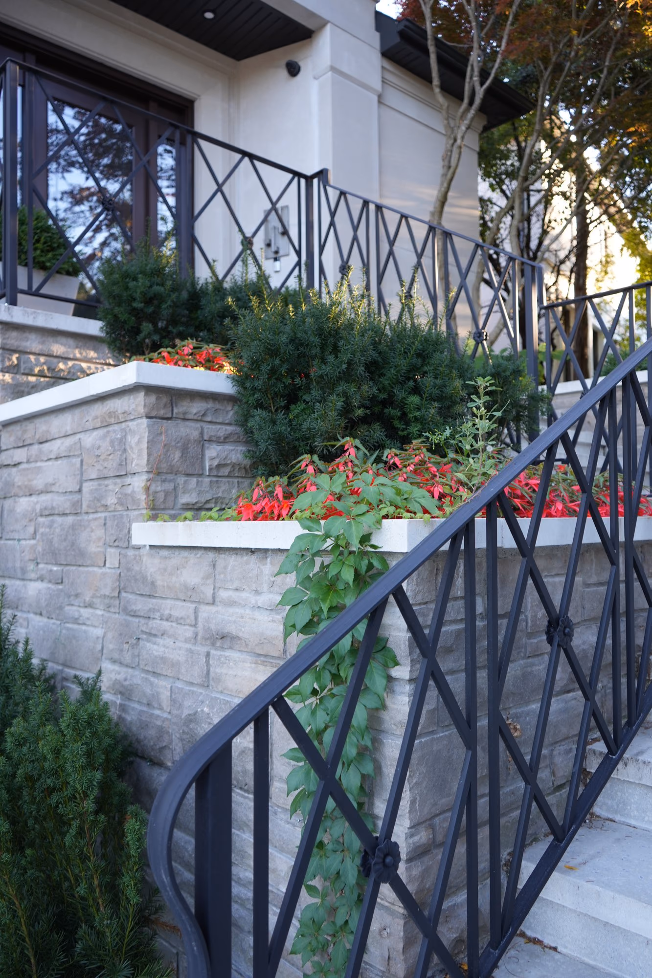Stone garden wall with iron railing and red flowers