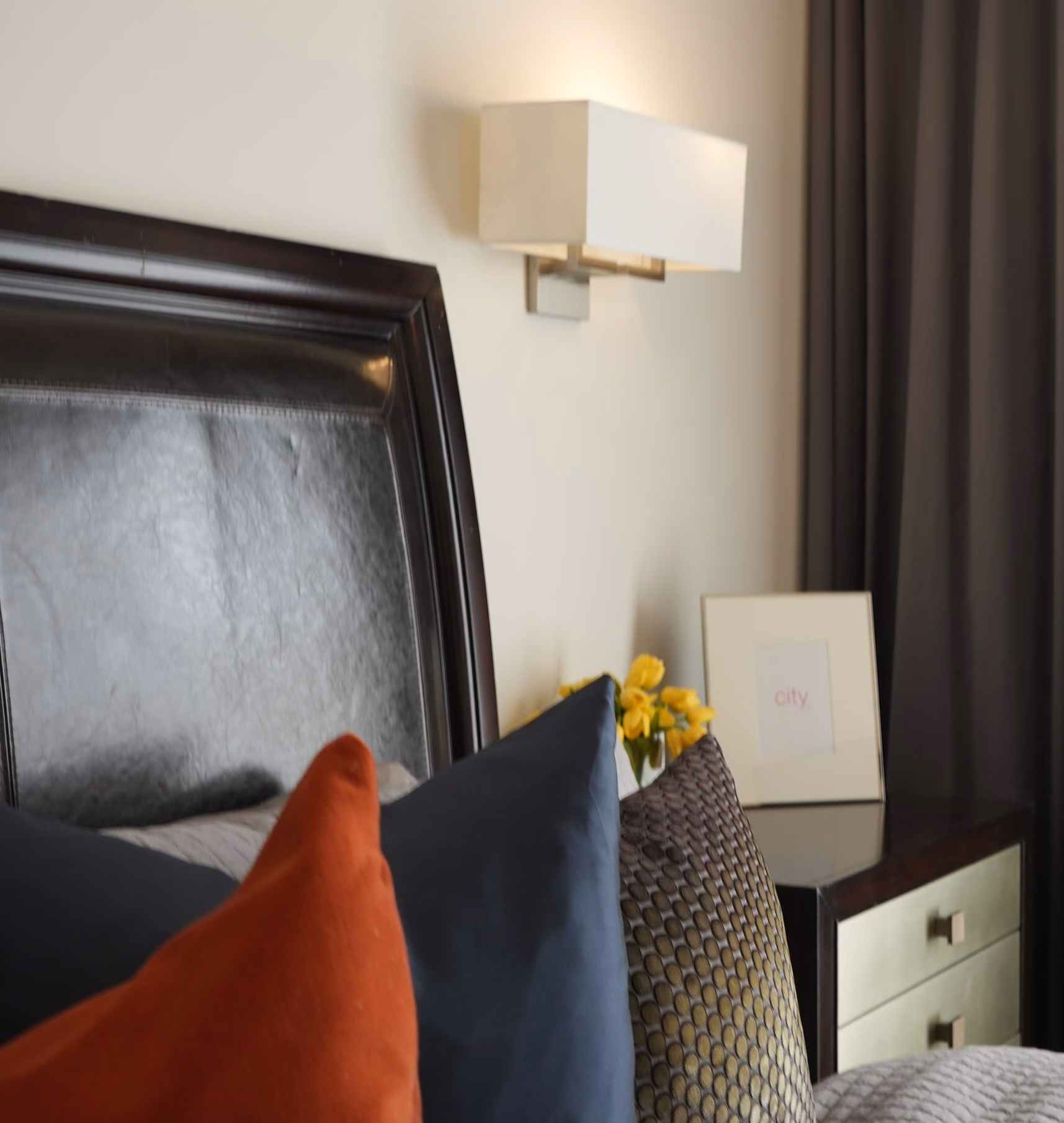 Bedroom detail with wall sconce and layered cushions