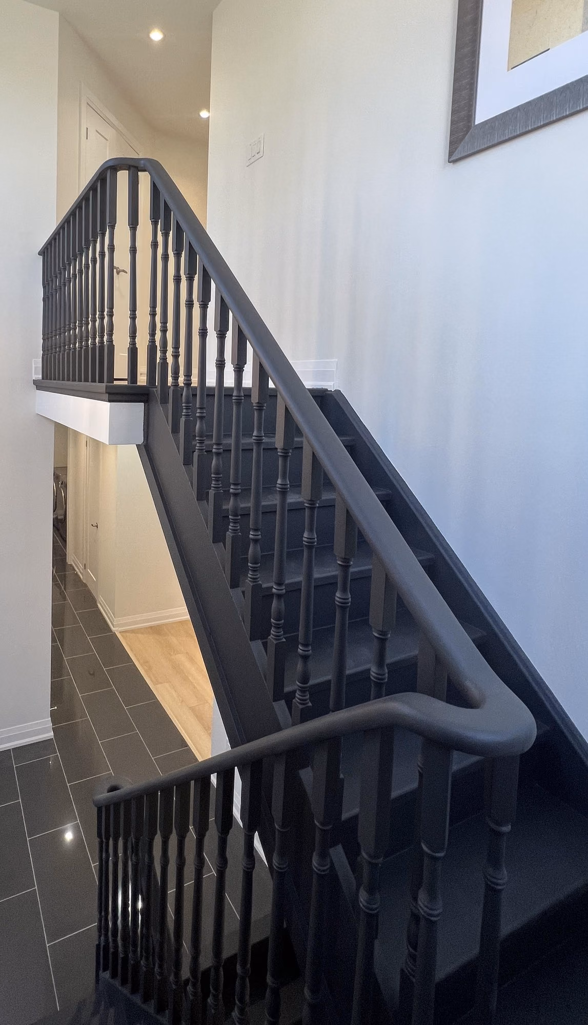 Renovated staircase with black railing and lantern pendants