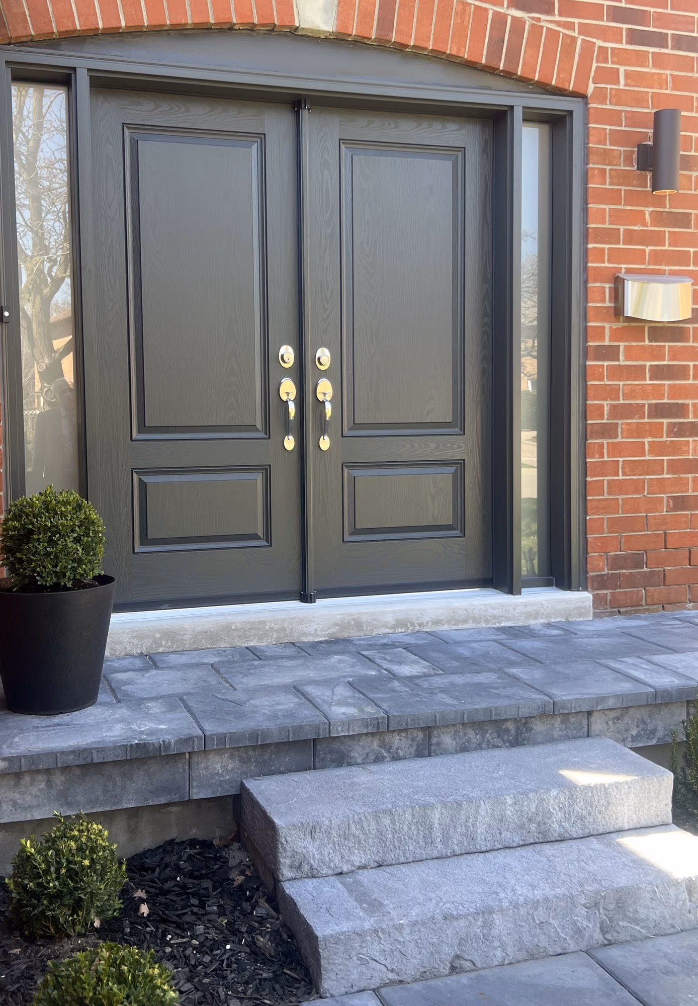 Renovated front entrance with dark double doors and brick facade